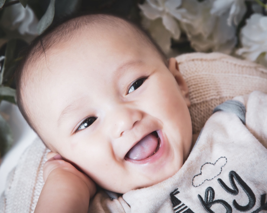 Close Up Shot Of A Cute Caucasian Baby Boy Surrounded By Flowers